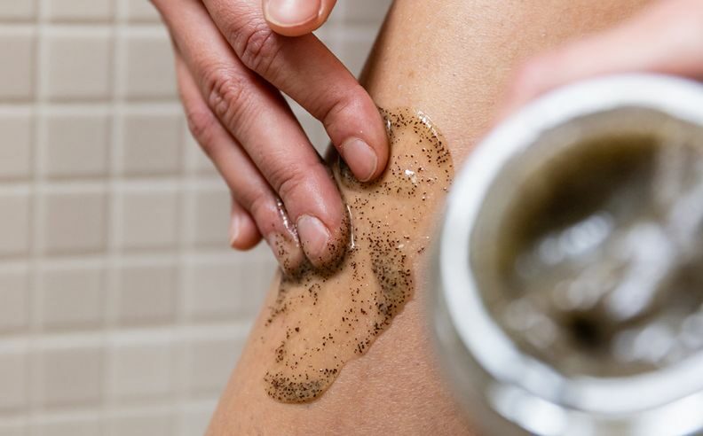 femme exfoliant la peau de ses jambes grâce à un exfoliant mécanique