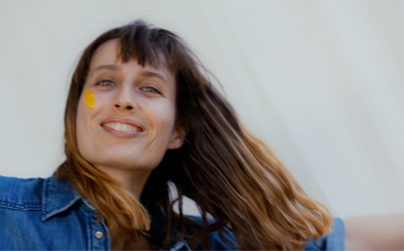 Zoom sur le visage joyeux d'une femme qui s'applique la crème glow