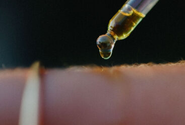 Zoom sur la peau d'une femme et une pipette d'huile Matière Brute Lab