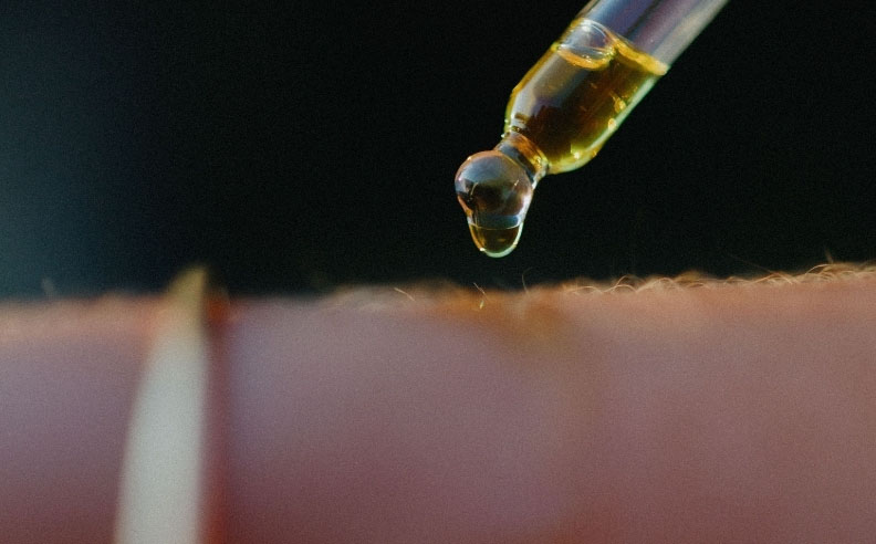 Zoom sur la peau d'une femme et une pipette d'huile Matière Brute Lab