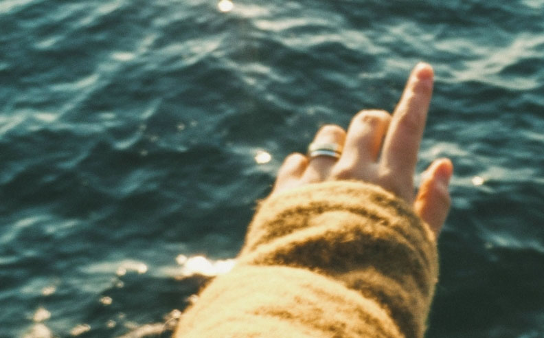 Zoom sur la main d'une femme qui pointe vers la mer