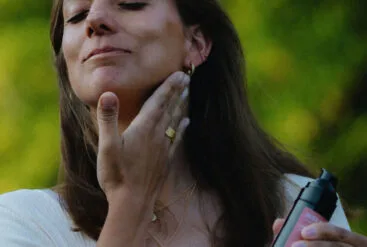 Zoom sur le visage heureux d'une femme qui s'applique la crème régénérante Matière Brute Lab