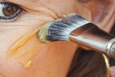 Zoom sur la pommette d'une femme qui s'applique le masque réparateur au miel