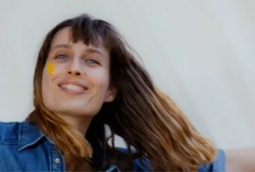 Zoom sur le visage joyeux d'une femme qui s'applique la crème glow