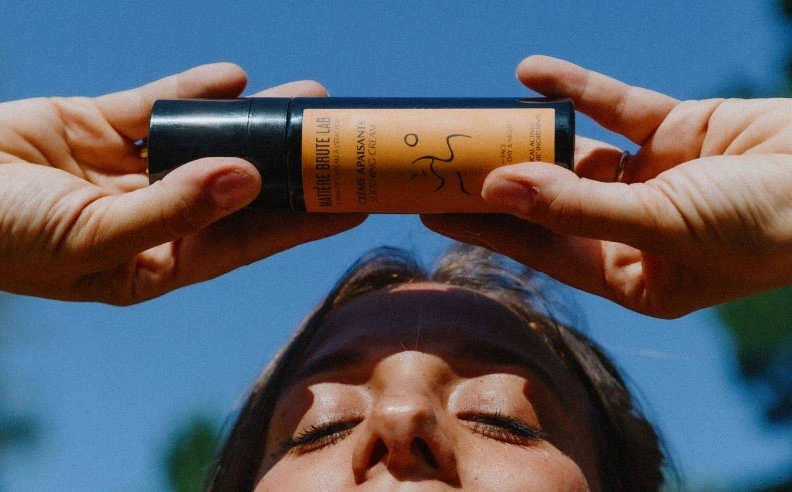 Zoom sur une femme qui tient dans ses mains la crème apaisante Matière Brute Lab