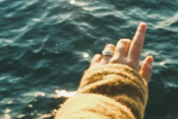Zoom sur la main d'une femme qui pointe vers la mer